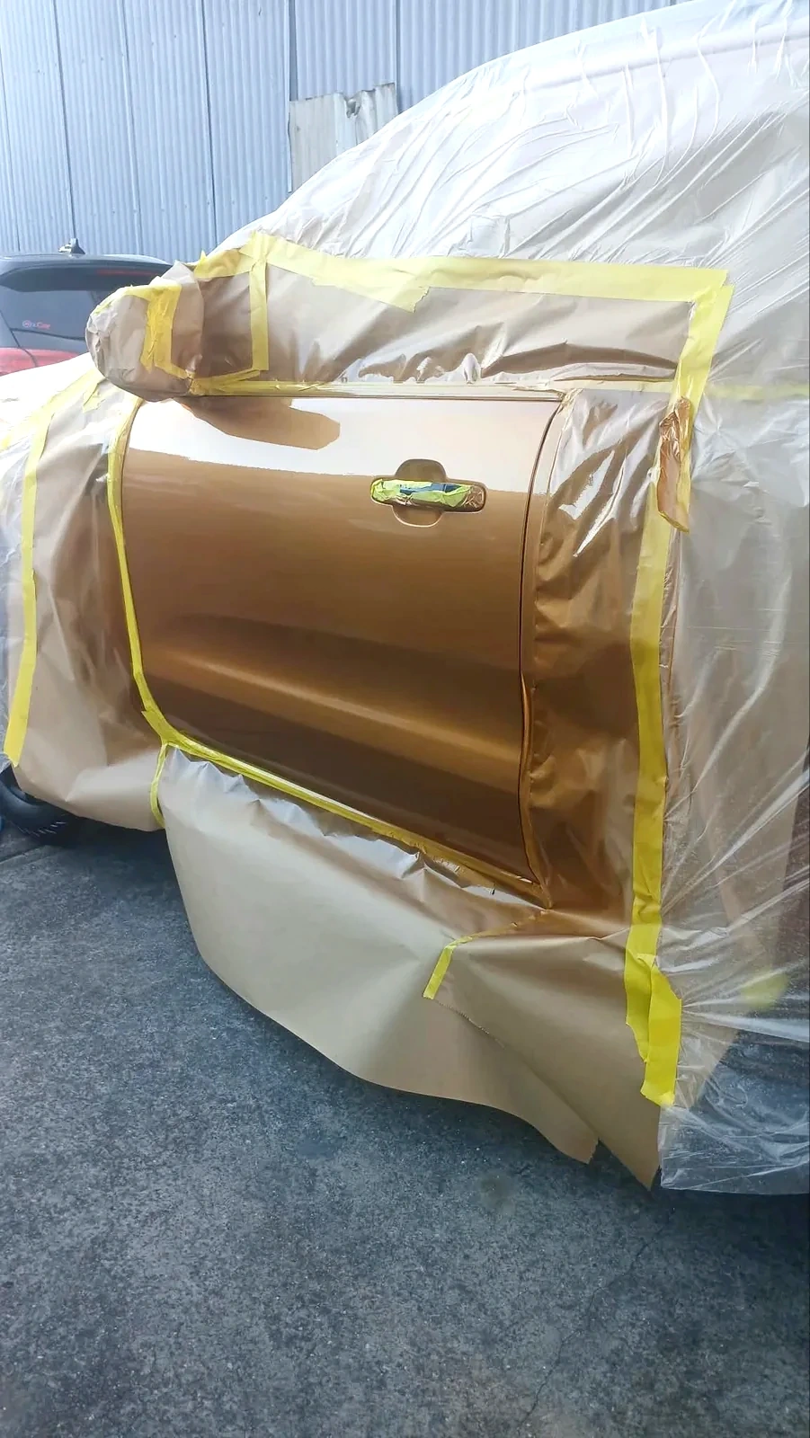 Gold ute door with fresh metallic paint finish and masking still in place