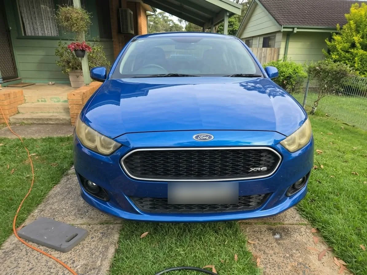 Blue Ford with cloudy yellow headlights before restoration, number plate obscured