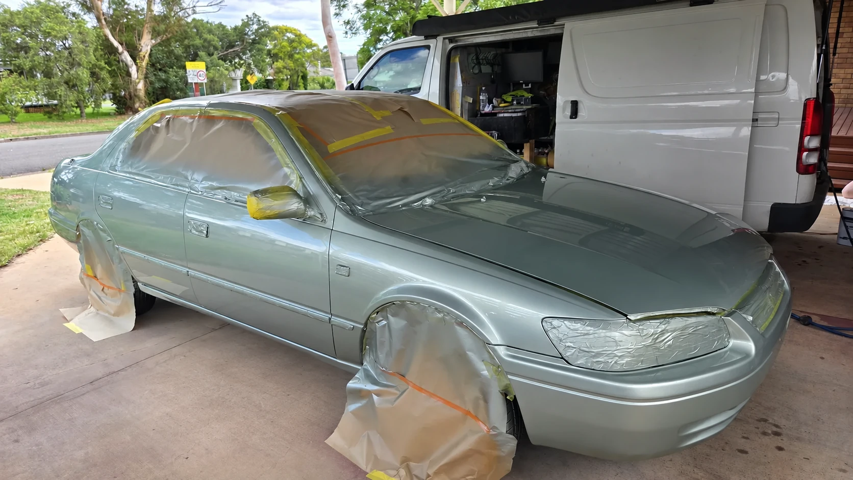 Metallic silver-green sedan following paintwork, with Zac's mobile work van behind it